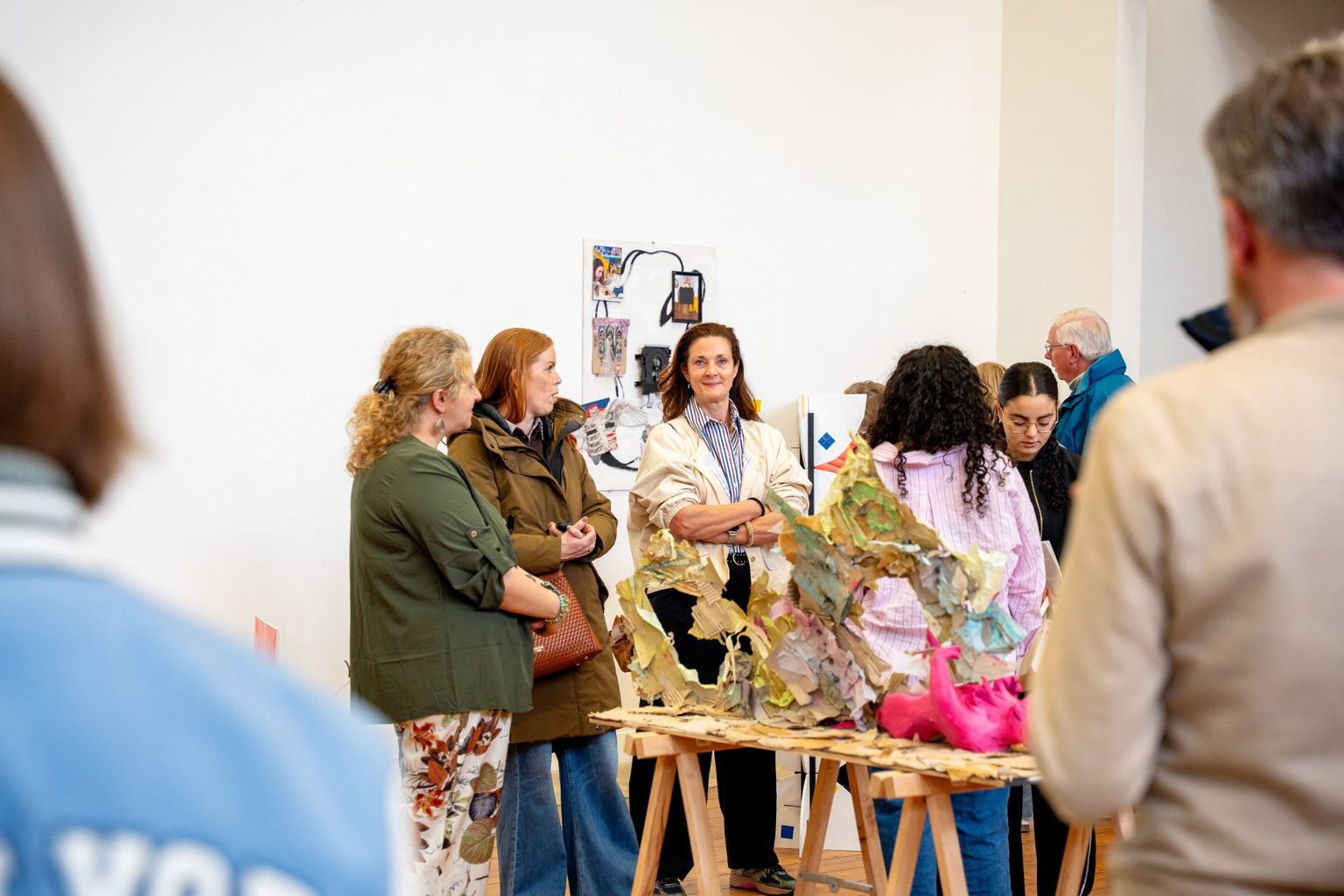 Mensen zijn met elkaar in gesprek in de expositieruimte voor beeldende werken.